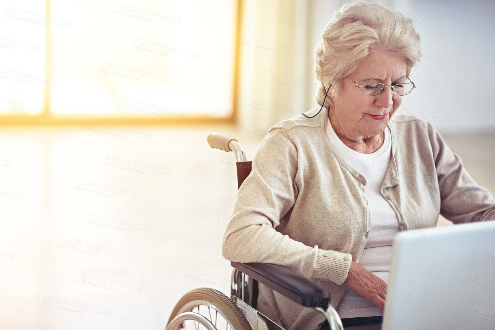 Buy stock photo Shot of a senior woman using a laptop while sitting in a wheelchair