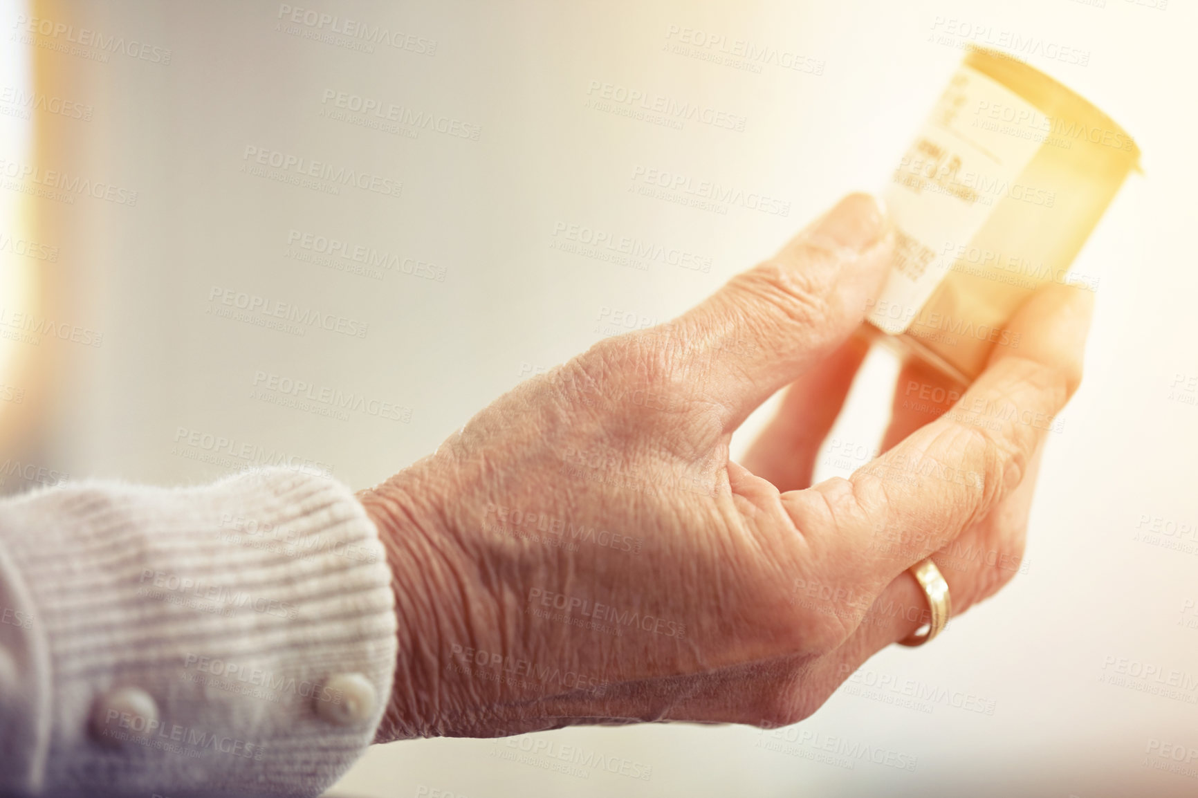 Buy stock photo Cropped shot of an elderly woman holding a container of medicine