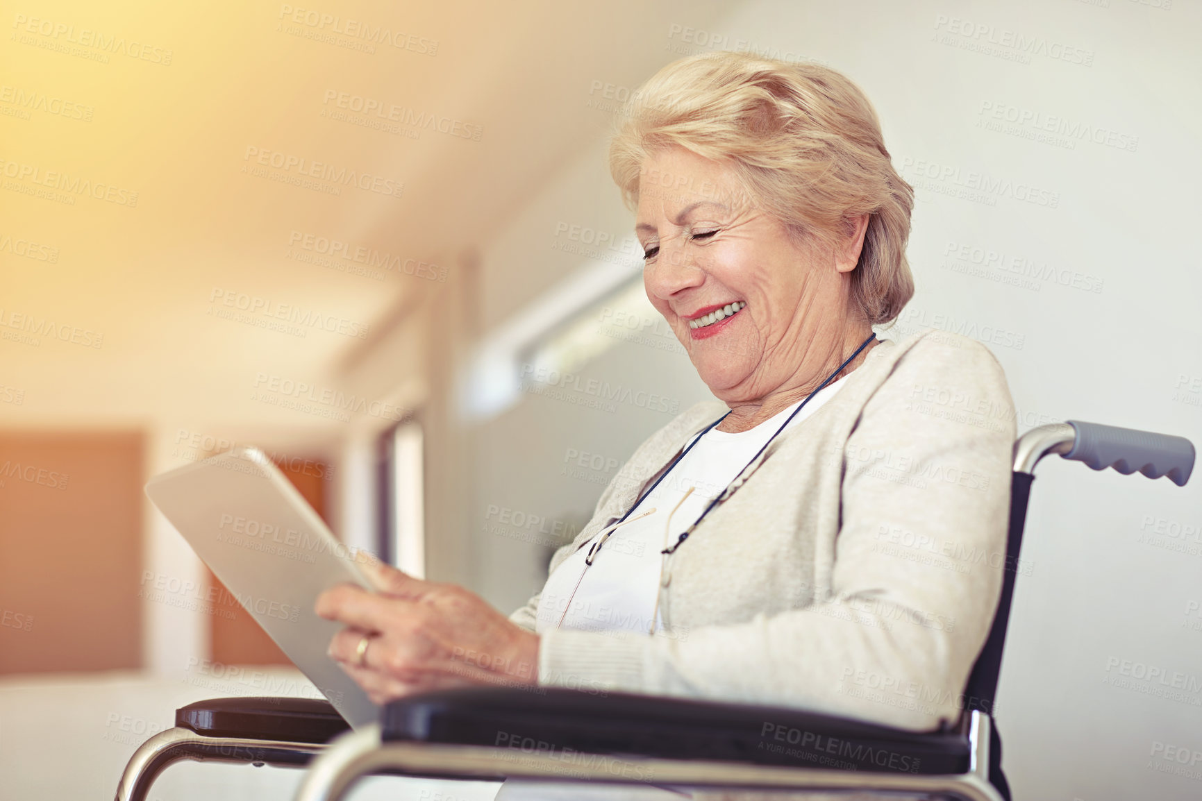 Buy stock photo Shot of a senior woman using a digital tablet while sitting in a wheelchair