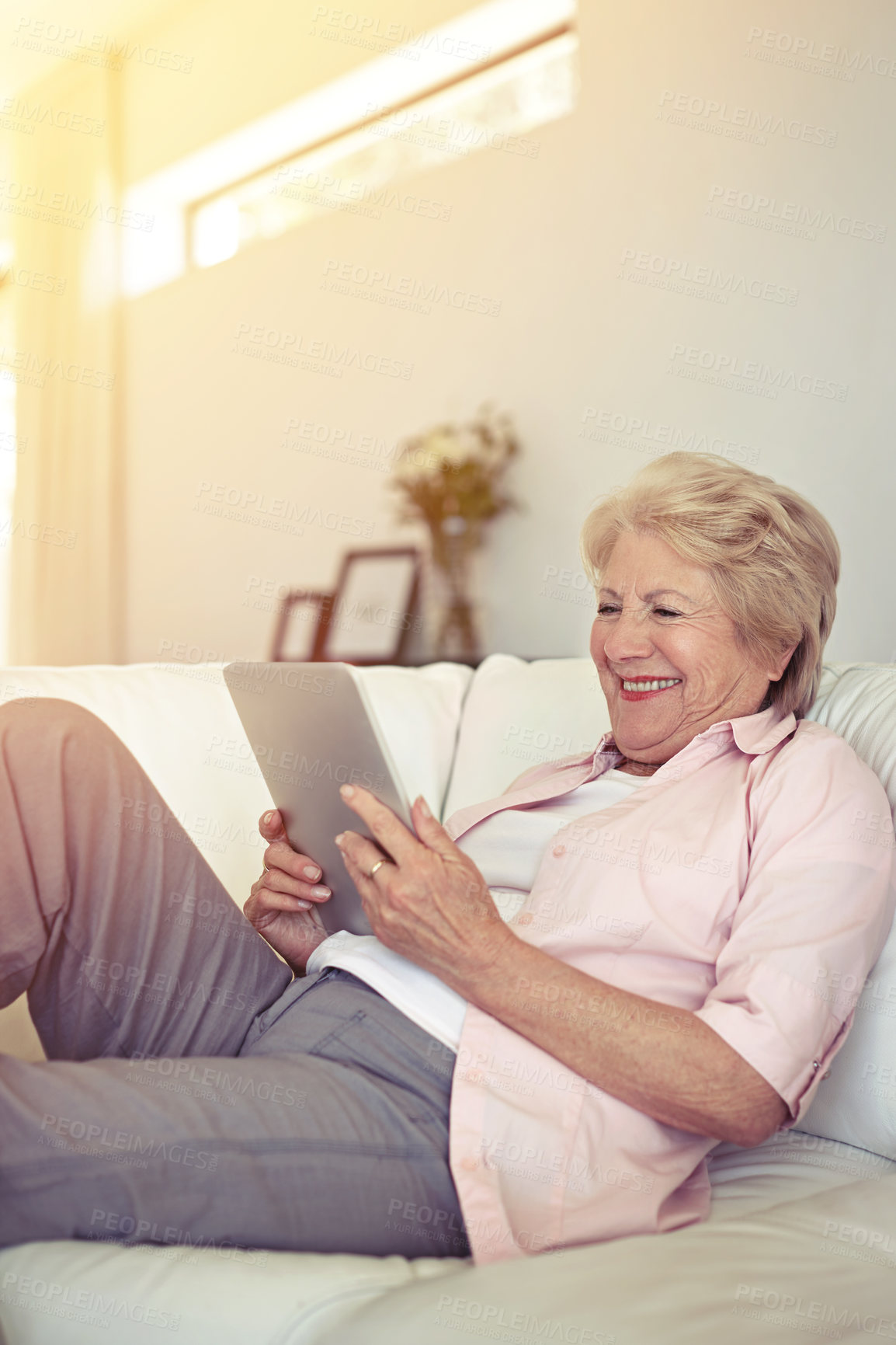 Buy stock photo Shot of a senior woman using her digital tablet at home