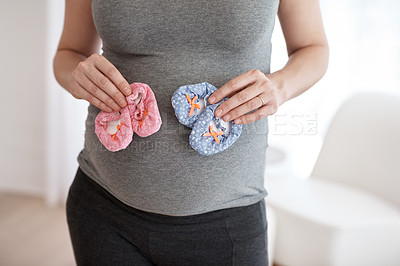 Buy stock photo Cropped shot of a pregnant woman holding baby shoes while standing in her home