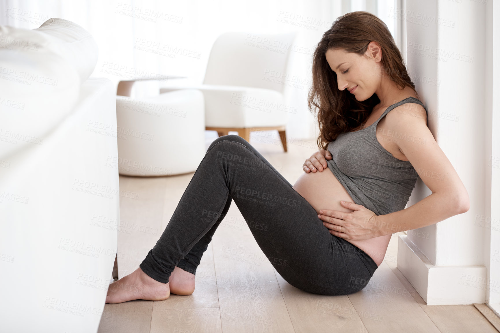 Buy stock photo Full length shot of a young pregnant woman sitting in her home