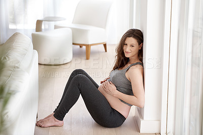 Buy stock photo Full length shot of a young pregnant woman sitting in her home