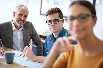 Buy stock photo Portrait of a young businessman sitting between his coworkers in a meeting
