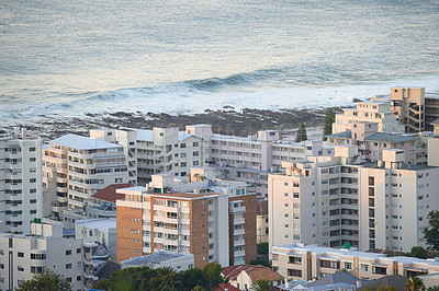 Buy stock photo Buildings, ocean and city for urban travel and skyscraper or luxury accommodation in morning. Sea or waves, development and hospitality for holiday or vacation and outdoor with landscape or coastline