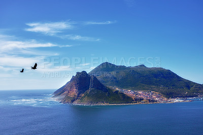 Buy stock photo Blue sky, clouds and mountain or ocean with buildings in nature or fishing village by sea. Coastal town, birds and waves or landscape in summer for travel, vacation and outdoor for holiday by beach