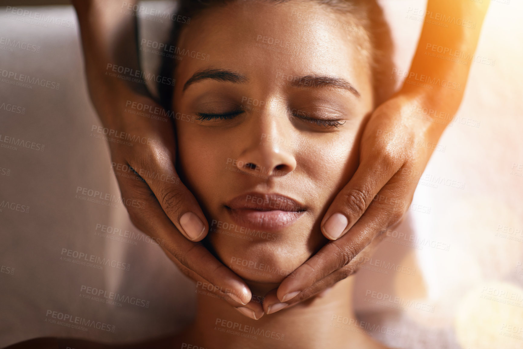 Buy stock photo Woman, spa and face massage on towel with hands and care for facial, wellness and beauty treatment on bed. Above, lens flare and african female person with skincare and relax at hotel with skin glow 