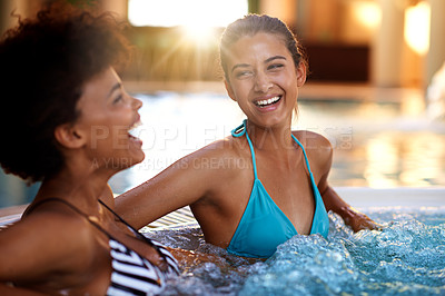 Buy stock photo Shot of two young women relaxing in a jacuzzi