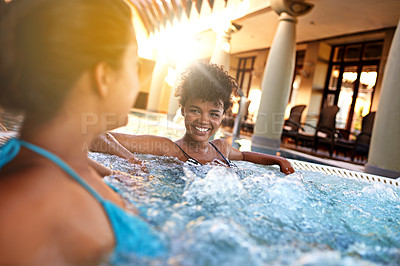 Buy stock photo Shot of two young women relaxing in a jacuzzi