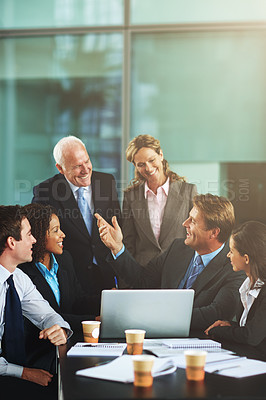 Buy stock photo Cropped shot of a group of businesspeople gathered around a laptop in the office