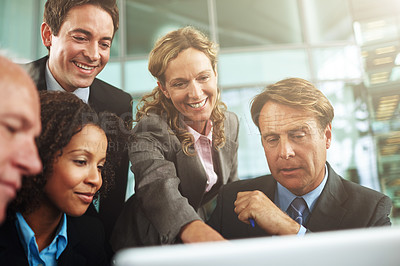 Buy stock photo Cropped shot of a group of businesspeople gathered around a laptop in the office