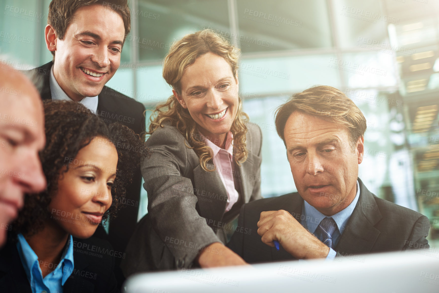 Buy stock photo Cropped shot of a group of businesspeople gathered around a laptop in the office