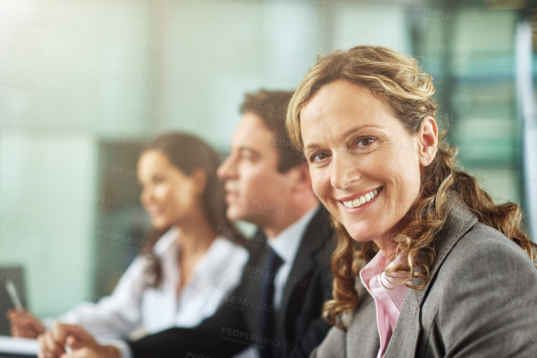 Buy stock photo Cropped shot of three businesspeople sitting behind a desk during a presentation