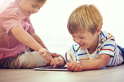 Buy stock photo Shot of two little boys using a digital tablet together while sitting on the floor