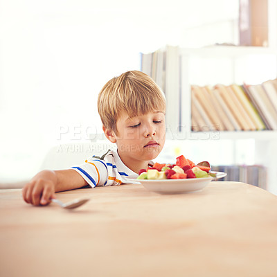 Buy stock photo A young boy looking at a bowl of fruit unenthusiastically