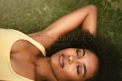 Buy stock photo Shot of a relaxed young woman lying on the grass with her eyes closed