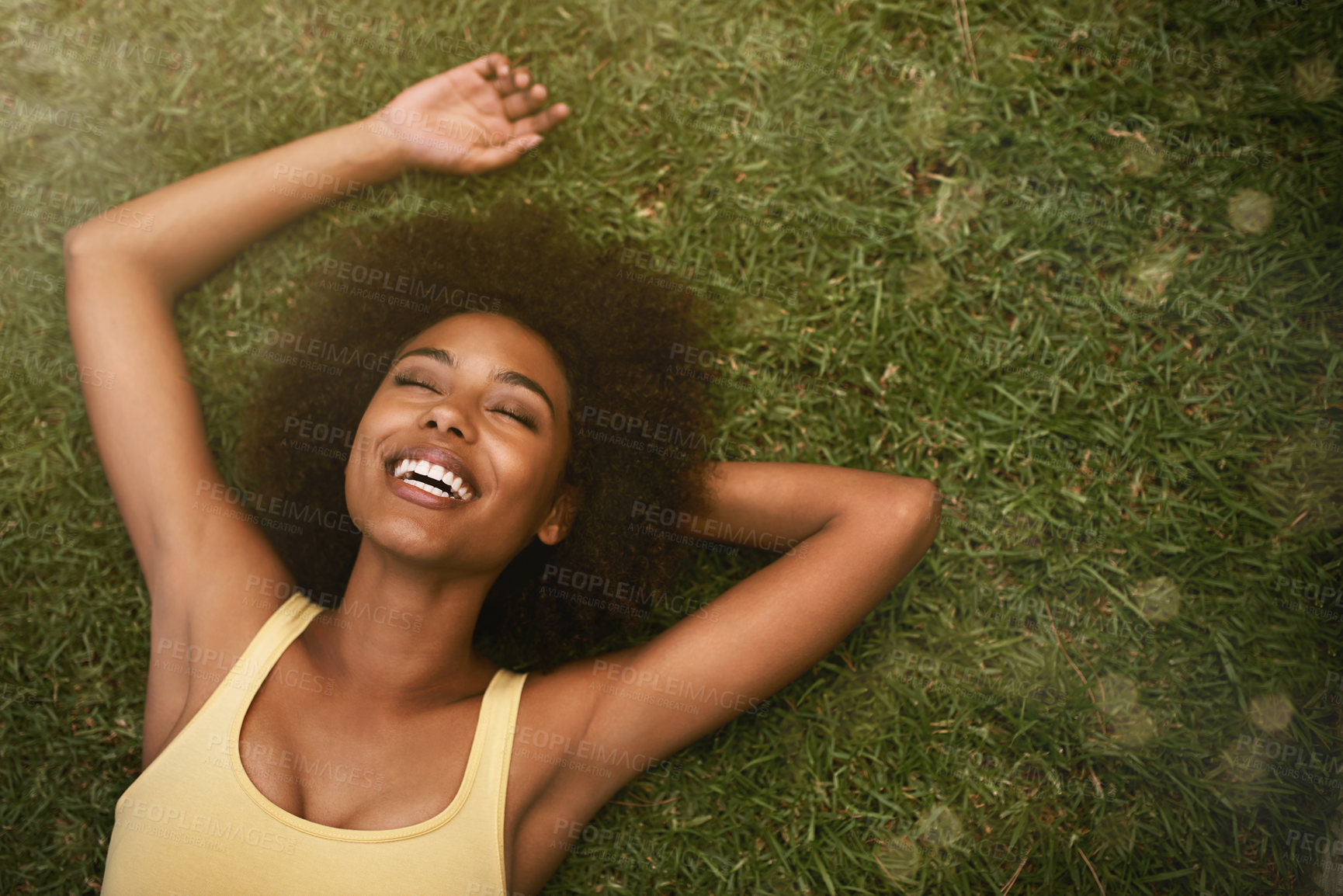 Buy stock photo Shot of a young woman laughing while relaxing on the grass