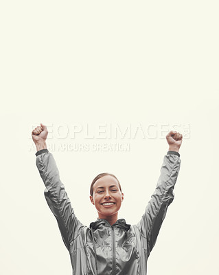 Buy stock photo Shot of a young woman standing with her arms raised in victory while out for an early morning run