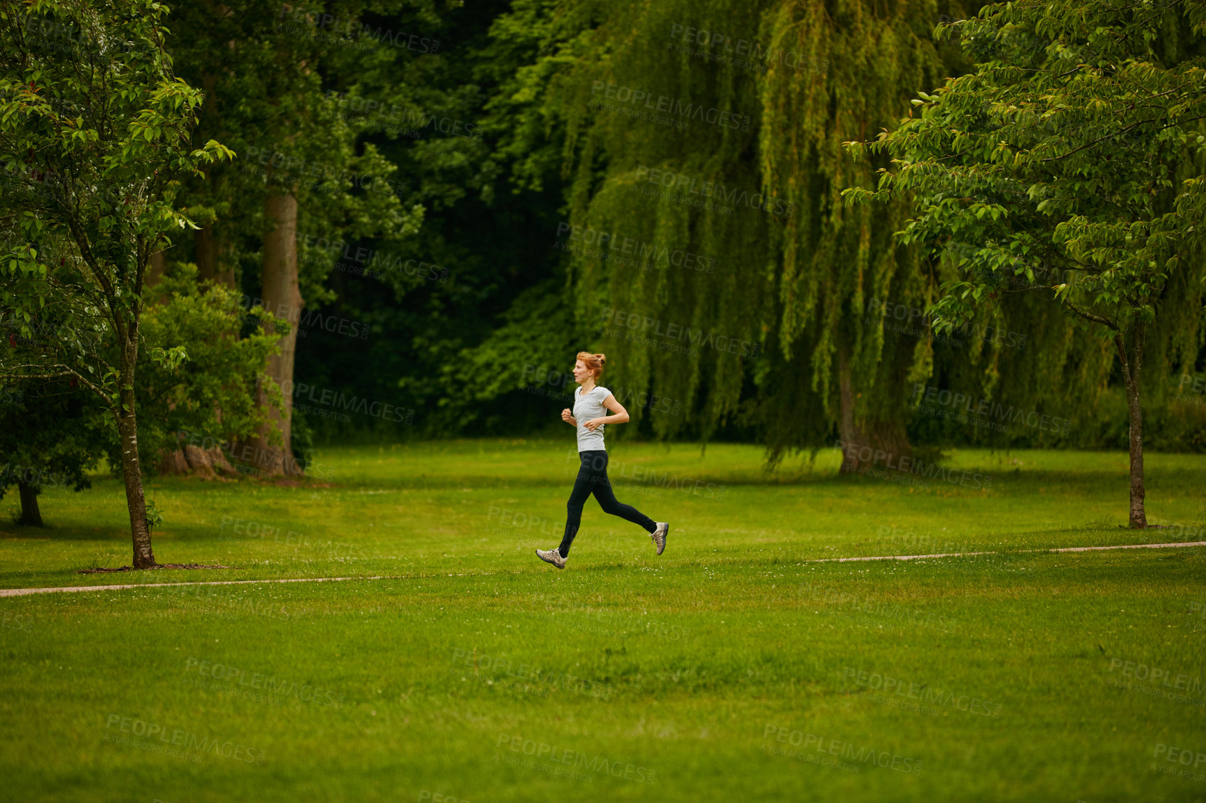 Buy stock photo Shot of a woman jogging in a park