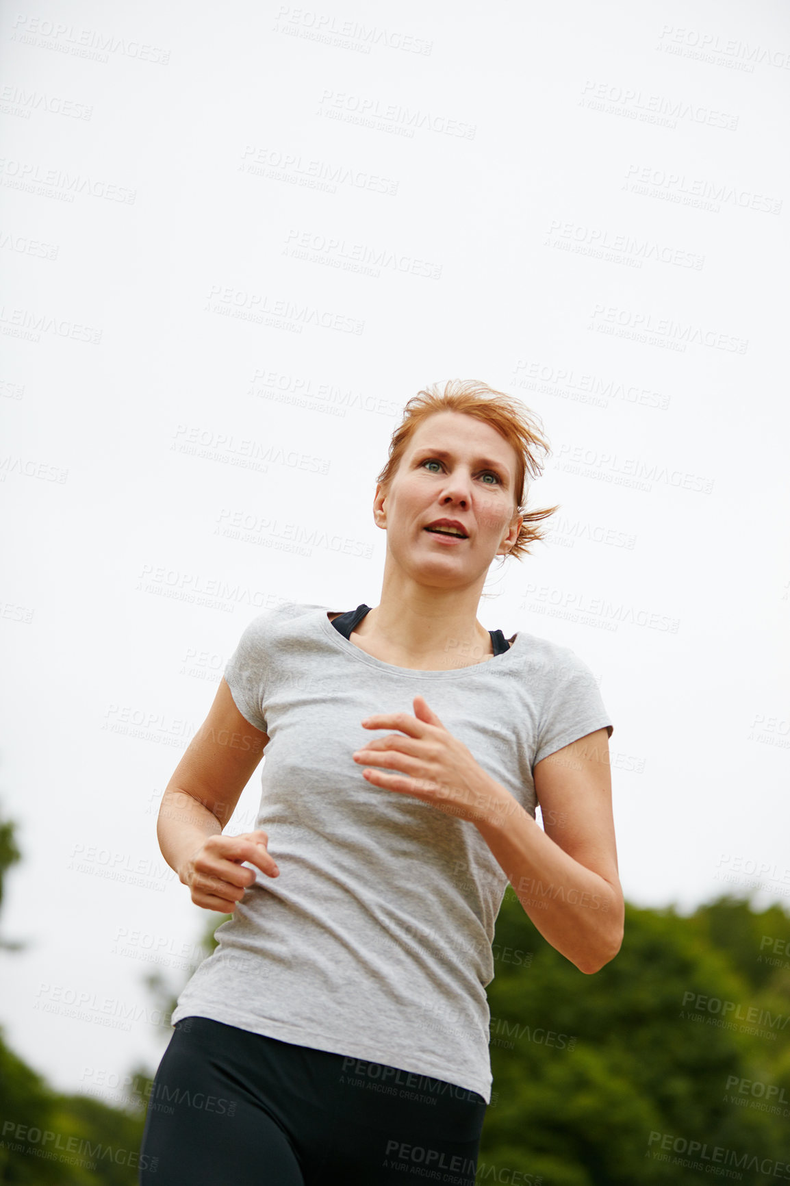 Buy stock photo Shot of a woman jogging in a park