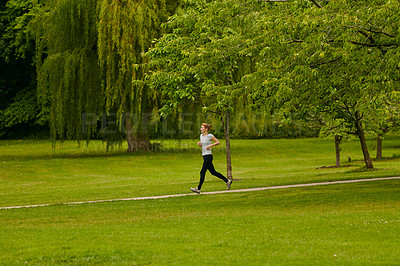 Buy stock photo Shot of a woman jogging along a foothpath in a park