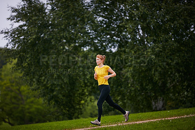 Buy stock photo Shot of a woman jogging along a foothpath in a park