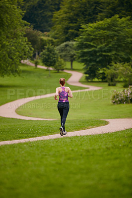 Buy stock photo Rearview shot of a woman jogging along a foothpath in a park