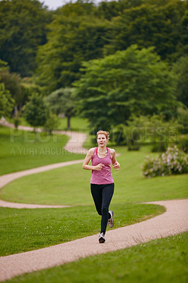 Buy stock photo Shot of a woman jogging along a foothpath in a park