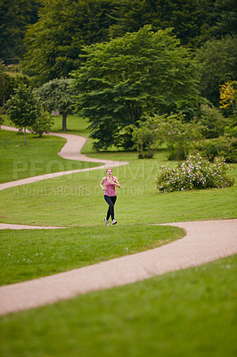 Buy stock photo Shot of a woman jogging along a foothpath in a park