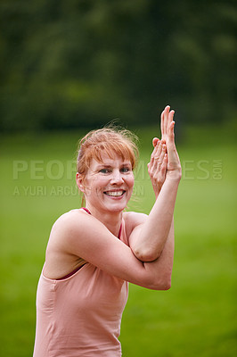 Buy stock photo Shot of a woman practicing yoga in a park