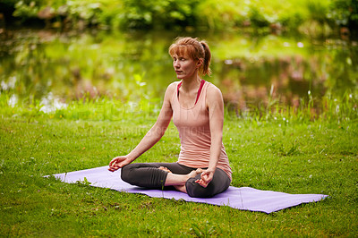 Buy stock photo Shot of a woman sitting in the lotus position in the park