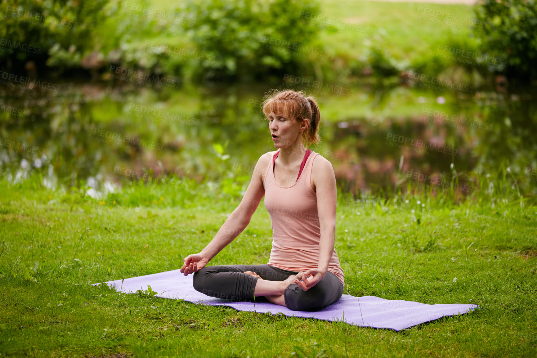 Buy stock photo Shot of a woman sitting in the lotus position in the park