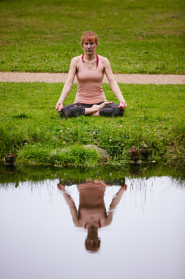 Buy stock photo Shot of a woman sitting in the lotus position in the park