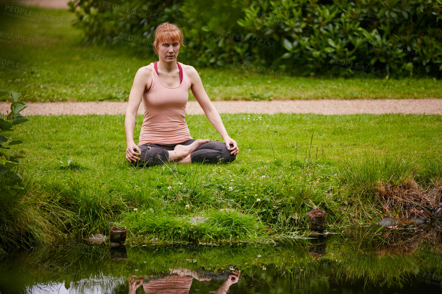 Buy stock photo Shot of a woman sitting in the lotus position in the park