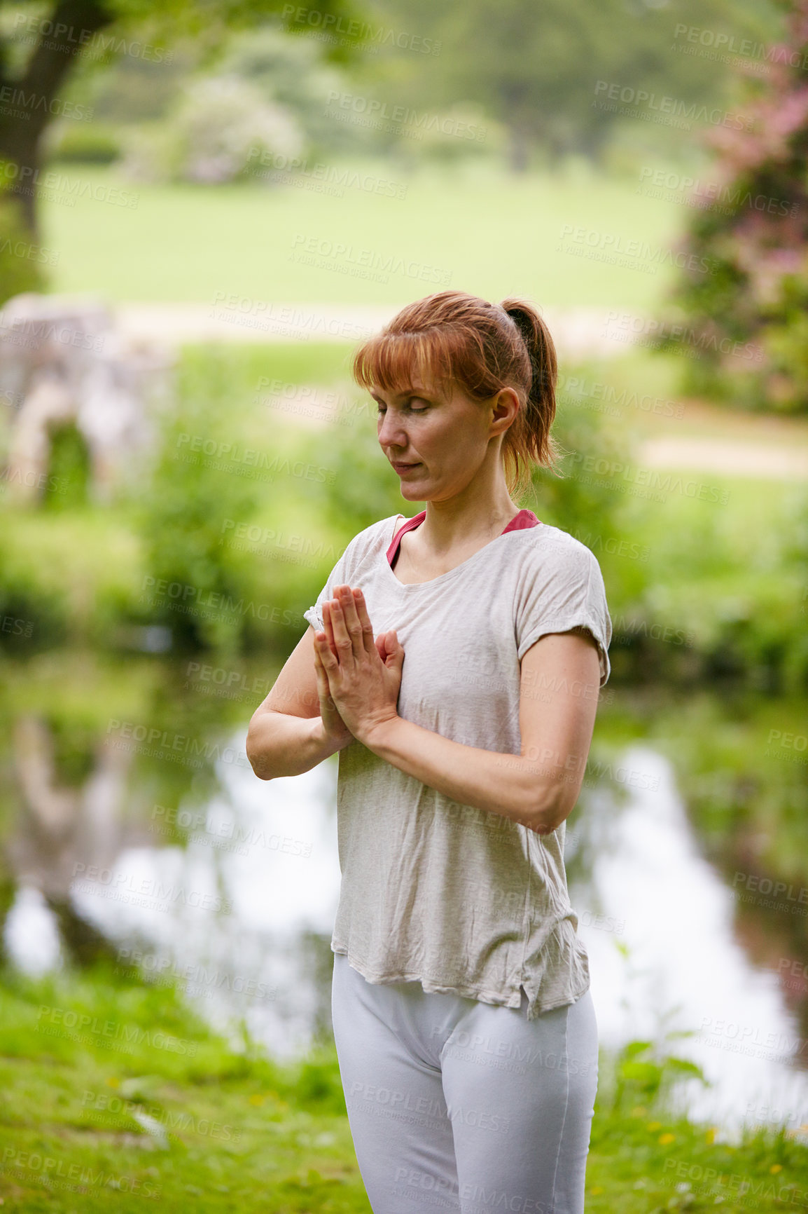 Buy stock photo Shot of a woman practicing yoga in a park