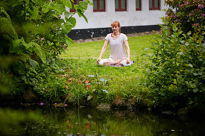 Buy stock photo Shot of a woman sitting in the lotus position in her backyard