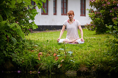 Buy stock photo Shot of a woman sitting in the lotus position in her backyard