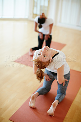 Buy stock photo Shot of two women doing yoga together in a studio