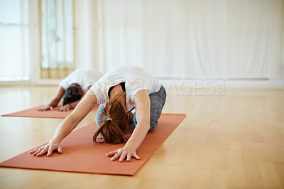 Buy stock photo Shot of two women doing yoga together in a studio