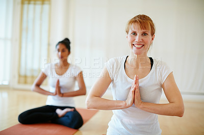 Buy stock photo Shot of two women doing yoga together in a studio