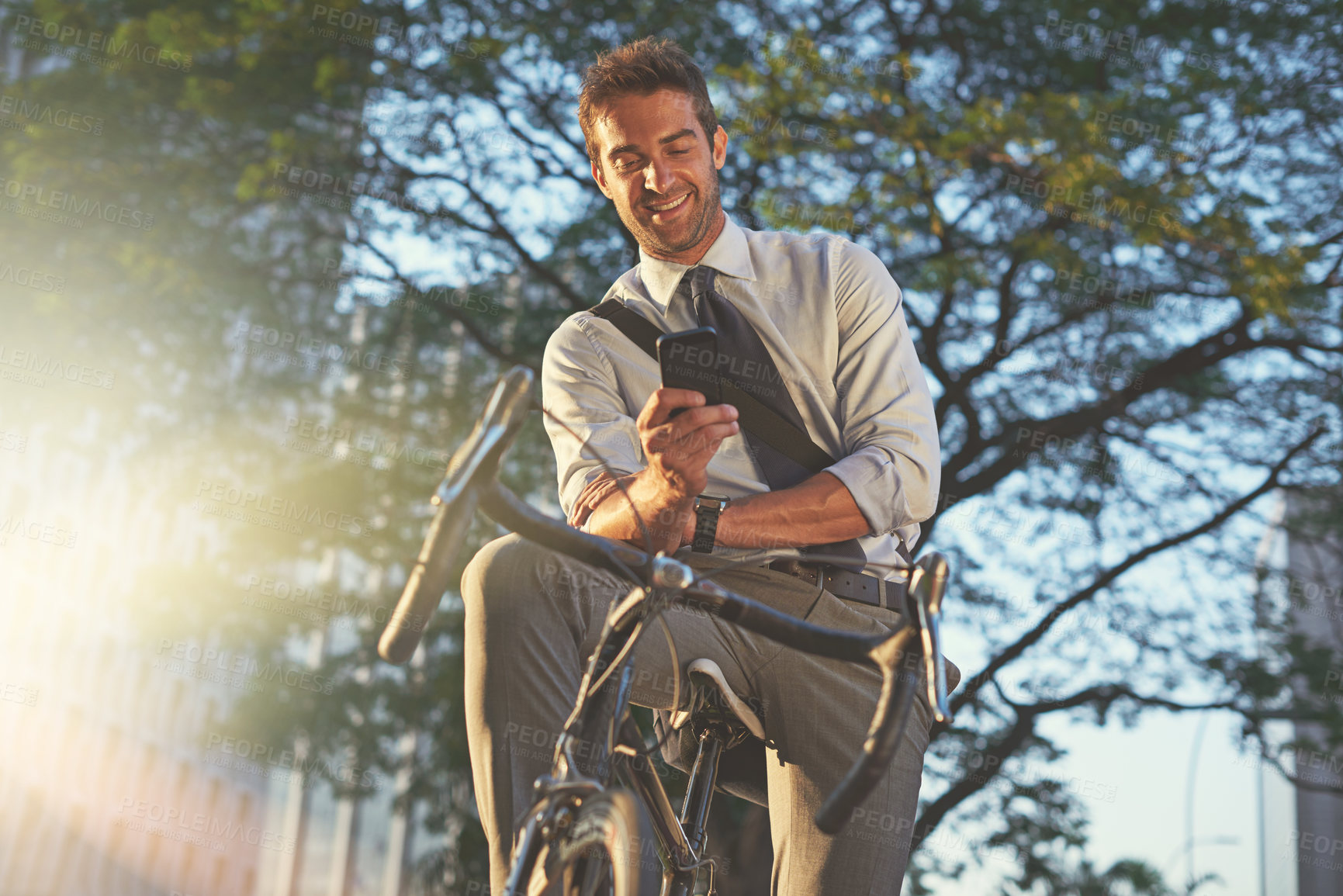 Buy stock photo Shot of a businessman using his cellphone while commuting to work with his bicycle