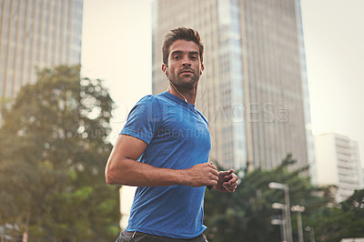 Buy stock photo Shot of a young man jogging through the city