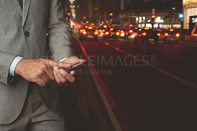 Buy stock photo Cropped shot of a businessman texting while standing beside a busy road