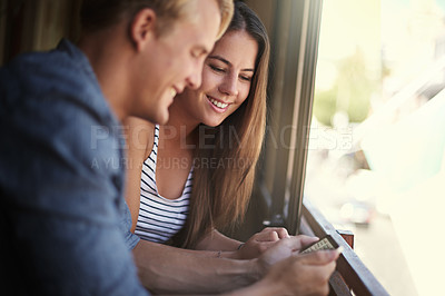 Buy stock photo Phone, love and social media with couple in coffee shop, at window for communication or dating. Smile, app or text message with happy young woman and woman in cafe or restaurant for texting together