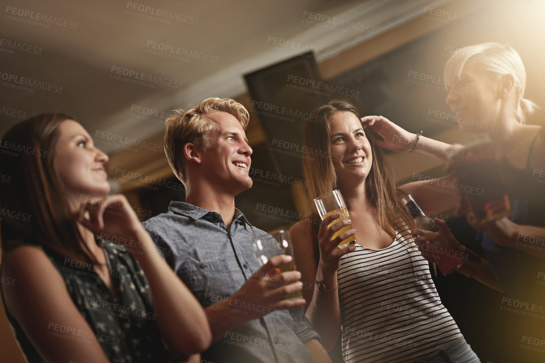 Buy stock photo Shot of a group of friends enjoying themselves in the bar
