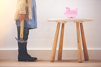 Buy stock photo A little girl standing next to her piggy bank with a hammer