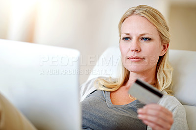 Buy stock photo Shot of a woman doing some online shopping on her sofa at home