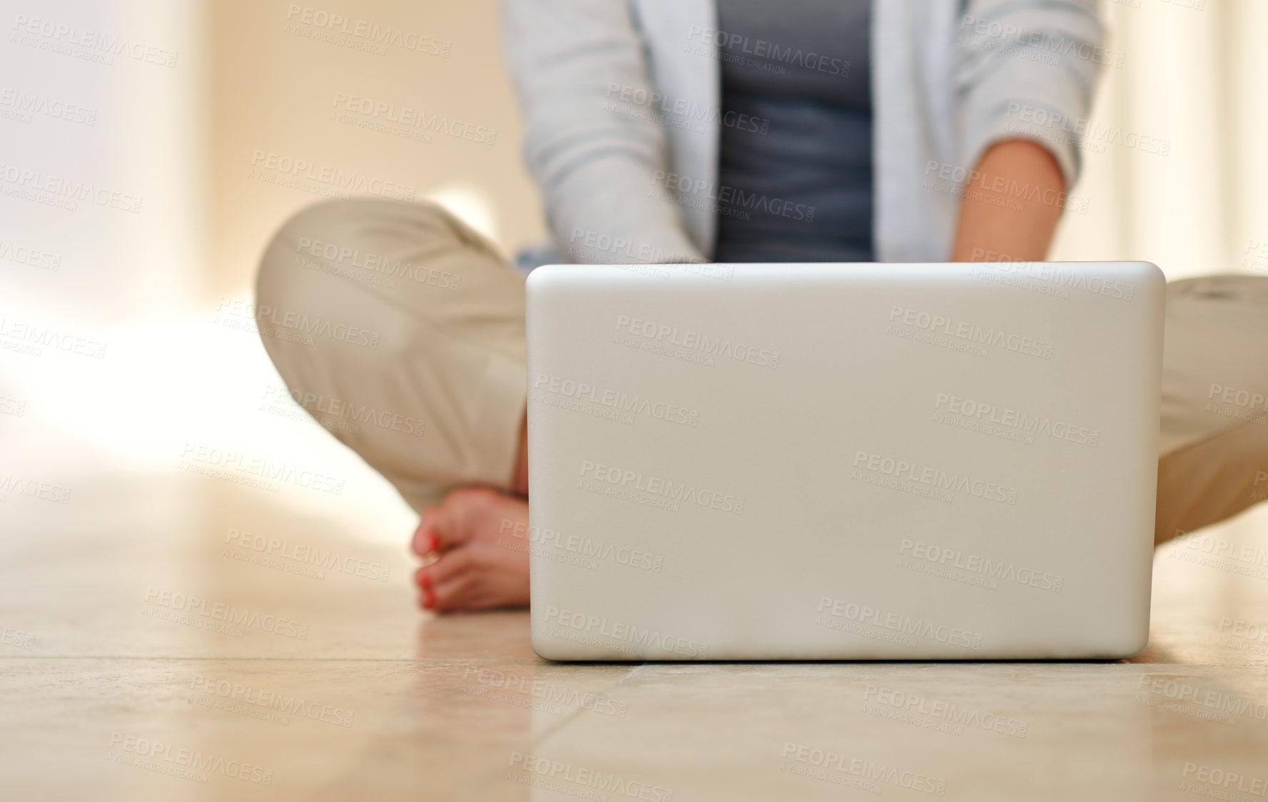 Buy stock photo Cropped shot of a woman using a laptop while sitting on her living room floor