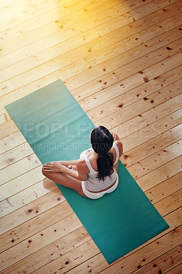Buy stock photo High angle shot of a young woman doing yoga indoors