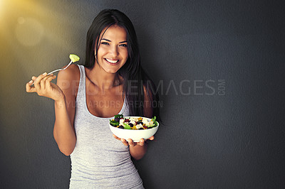 Buy stock photo Portrait of a healthy young woman eating a salad against a gray background